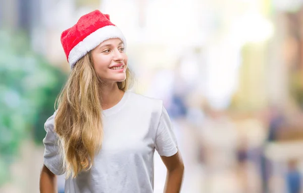 若い美しいブロンドの女性の上クリスマスの帽子をかぶっては 背景が笑顔で側に自然な表現の顔に離れて見て分離 自信を持って笑ってください — ストック写真