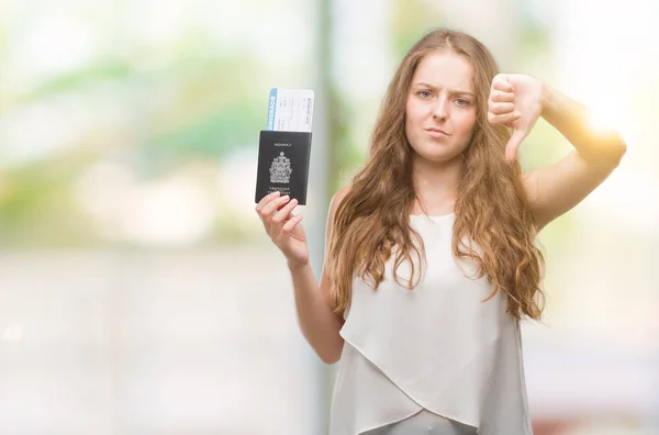 若いブロンドの女性持株パスポート カナダの怒った顔 ダウン親指で嫌悪感を示すマイナス記号 拒絶反応の概念と搭乗券 — ストック写真