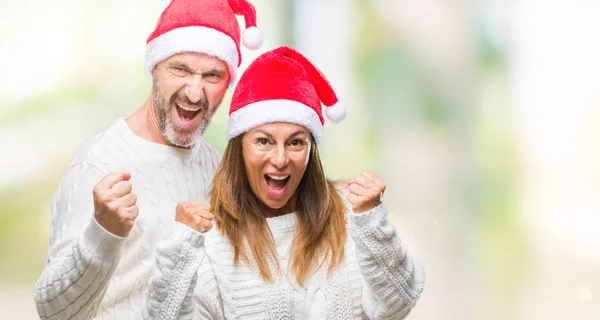 中年ヒスパニック系カップルは非常に幸せと興奮して腕を上げると 笑みを浮かべて 成功のために叫んで勝者ジェスチャーを行う分離の背景にクリスマス帽子をかぶっています お祝いのコンセプト — ストック写真
