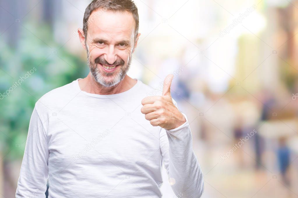 Middle age hoary senior man wearing white t-shirt over isolated background doing happy thumbs up gesture with hand. Approving expression looking at the camera with showing success.