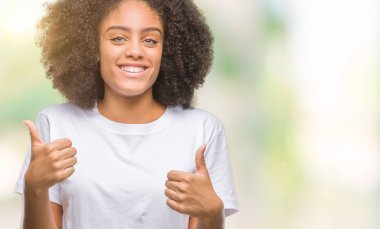 İzole arka plan başarı işareti el ile olumlu hareketi yaparken Genç afro Amerikan kadın başparmak gülümseyen ve mutlu. Neşeli bir ifadeyle, kazanan jest kameraya bakıyor.