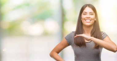 Büyük ve büyük boy işaret, ölçü birimi sembol gösteren el eller genç güzel İspanyol kadın. Kameraya bakarak gülümsüyordu. Ölçüm kavramı.