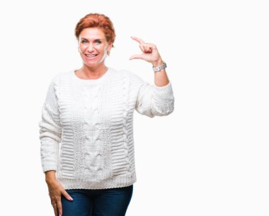 İzole arka plan gülümseyen ve boyutu işaret parmaklı ararken ve kamera işi el ile kendinden emin eller üzerinde kış kazak giyen Atrractive üst düzey beyaz Kızıl saçlı kadın. Ölçü kavramı.