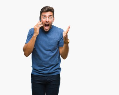 Smartphone üzerinde kocaman bir gülümseme ile çığlık zaferini kutluyor ve ellerini kaldırdı izole arka plan çok mutlu ve heyecanlı, kazanan ifade üzerinde konuşan genç yakışıklı adam