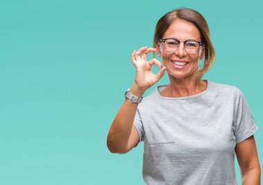 İzole arka plan el ve parmaklar ok işaretiyle yapıyor olumlu gülümseyen üzerinde gözlük takan orta yaş İspanyol kadın kıdemli. Başarılı ifade.