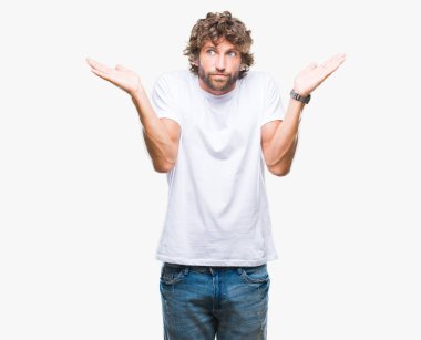 Yakışıklı İspanyol modeli adam izole arka plan clueless ve şaşkın bir ifadeyle kollar ve eller kaldırdı. Şüphe kavramı.