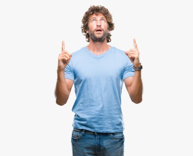 Yakışıklı İspanyol modeli adam izole arka plan üzerinden hayran ve yukarıya bakıp parmakları ile işaret şaşırttı ve silah kaldırdı.