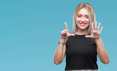 Genç Sarışın kadın gösterilen ve parmakları ile işaret izole arka plan yüzünden kendinden emin ve mutlu gülümseyerek süre yedi numara.