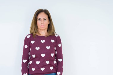 Üzerinde kalp kazak giyen güzel orta yaş kadın arka plan gevşek yüzünde ciddi bir ifade ile izole. Basit ve doğal kameraya bakıyor.