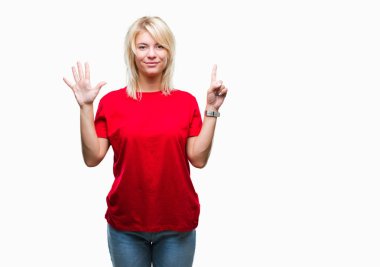 Gösterilen ve parmakları ile işaret izole arka plan üzerinde kırmızı t-shirt giyen genç güzel sarışın kadın kendinden emin ve mutlu gülümseyerek süre 6 numara.