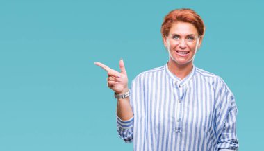 Yüzünde kocaman bir gülümseme ile izole arka plan Atrractive üst düzey beyaz Kızıl saçlı kadın kameraya bakarak yan el ve parmak ile işaret.