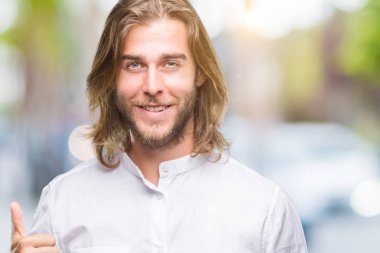 Yakışıklı delikanlı hareketi el ile mutlu yaşasın yapıyor izole arka plan üzerinde uzun saçlı. Kameraya bakarak başarı gösteren ile ifade onaylama.