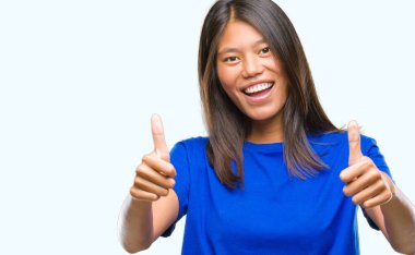 Genç Asyalı kadın el ile pozitif jest yapıyor onaylama izole arka plan üzerinde başparmak gülümseyen ve başarı için mutlu. Kamera, kazanan jest arıyorsunuz.
