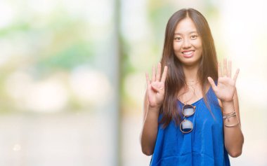 Genç Asyalı kadın gösterilen ve parmakları ile işaret izole arka plan üzerinde numara 9 kendinden emin ve mutlu gülümseyerek süre.