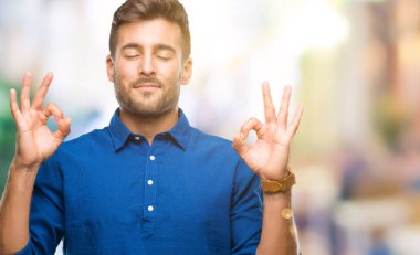 Yakışıklı delikanlı izole arka plan üzerinde dinlenmek ve gülümseyen gözlerle parmak ile meditasyon jest yapıyor kapalı. Yoga kavramı.