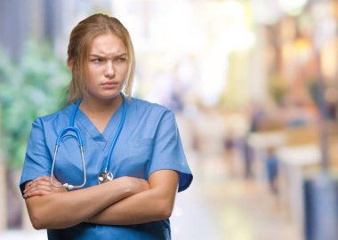 İzole arka plan şüpheci ve sinir, onaylamayan ifade yüz çapraz kolları olan cerrah üniforma giyen genç beyaz doktor kadın. Negatif kişi.