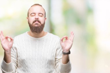 Genç beyaz hipster adam giyen kış kazak izole arka plan üzerinde dinlenmek ve gülümseyen gözlerle kapalı parmak jestle meditasyon yapıyor. Yoga kavramı.
