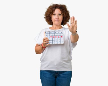 Adet takvim açık eliyle dur işareti ile ciddi ve kendine güvenen ifade, savunma jest yapıyor izole arka plan üzerinde tutan orta ager üst düzey kadın