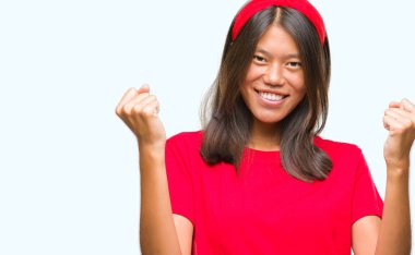 Genç Asyalı kadın kutluyor izole arka plan üzerinde şaşırttı ve başarı için kaldırdı kollarını açarak hayret ve gözleri açık. Kazanan kavramı.