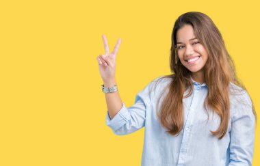 Genç güzel esmer iş kadını mutlu yüz zafer işareti yaparken kameraya göz kırpıyor ile gülümseyen izole arka plan üzerinde. İki numaralı.