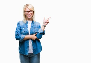 Kameraya bakarak yan el ve parmak ile işaret yüzünde kocaman bir gülümseme ile izole arka plan üzerinde gözlük takan genç güzel sarışın kadın.