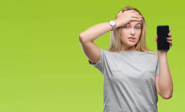 Young caucasian woman showing screen of smartphone over isolated background stressed with hand on head, shocked with shame and surprise face, angry and frustrated. Fear and upset for mistake.