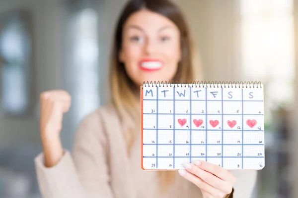 Young Beautiful Woman Holding Menstruation Calendar Home Screaming Proud Celebrating — Stock Photo, Image