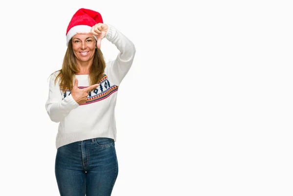 笑顔の幸せそうな顔で指と手作りフレーム分離の背景に冬のセーターと Chrismat 帽子身に着けている中年の成人女性 創造性と写真のコンセプト — ストック写真