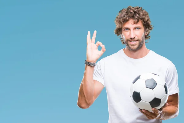 優秀なシンボルの指で サインをして孤立した背景にサッカー サッカー ボールを保持しているハンサムなヒスパニック系男性モデル — ストック写真