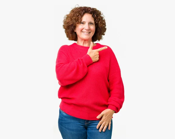 手と顔に幸せで自然な表現のある側までの指で指している顔の笑顔で陽気な分離の背景に美しい中間エイガー シニア女性赤冬セーター — ストック写真