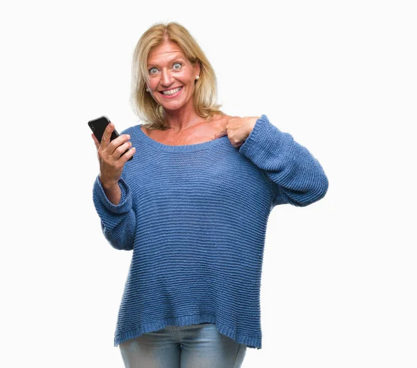 中年の金髪女性自分自身に驚き顔人差し指と孤立の背景にスマート フォンを使用してメッセージを送信します — ストック写真