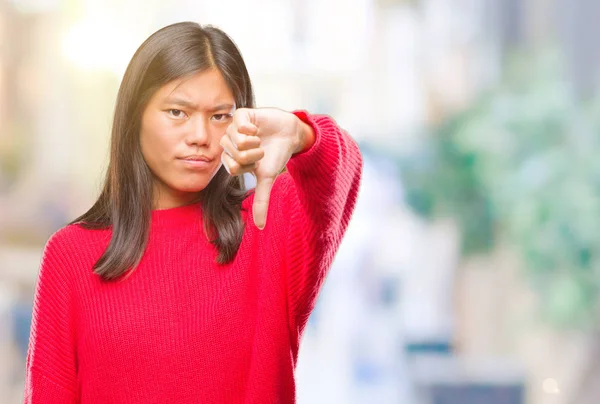 年轻的亚洲妇女穿着冬季毛衣在孤立的背景看不高兴和愤怒显示拒绝和否定与拇指向下手势 错误的表达式 — 图库照片