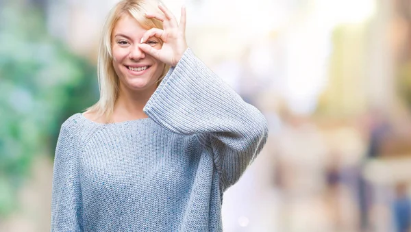 手の笑顔 幸せそうな顔で指を通して見る目で のジェスチャーを行う分離の背景に冬のセーターを着ている若い美しいブロンドの女性 — ストック写真