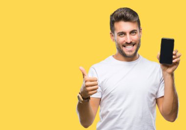 Yakışıklı delikanlı izole arka plan üzerinde Smartphone ekran ok işareti, başparmak ile parmak, mükemmel işareti yapıyor kocaman bir gülümseme ile mutlu gösterilen