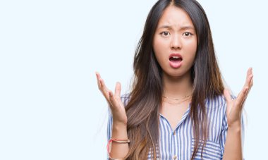 Genç Asyalı kadın izole arka plan çılgın ve kızgın bağırarak ve agresif ifade ve silah kaldırdı bağırıyor. Hayal kırıklığı kavramı.