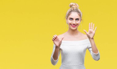 Genç güzel sarışın ve mavi gözlü kadın yüzünden arka plan gösteren izole ve parmakları ile işaret kendinden emin ve mutlu gülümseyerek süre 6 numara.