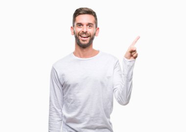 Kameraya bakarak yan el ve parmak ile işaret eden genç yakışıklı adam yüzünde kocaman bir gülümseme ile izole arka plan üzerinde.
