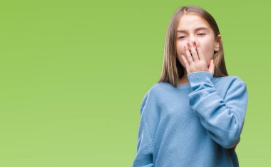 İzole arka plan üzerinde kış kazak giyen genç güzel kız el ağzıyla kapsayan yorgun esneme sıkılmış. Restless ve uyku hali.