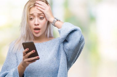 Sarışın genç kadın manifatura izole arka plan baş, el ile vurguladı üzerinden Smartphone kullanarak ileti gönderme şok utanç ve sürpriz suratla, öfkeli ve sinirli. Korku ve hata için üzgün.