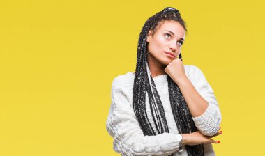 Genç örgülü saç Afro-Amerikan Kız çene düşünme hakkında soru, dalgın ifade üzerine el ile izole arka plan üzerinde kazak giyiyor. Düşünceli yüzüyle gülümsüyor. Şüphe kavramı.