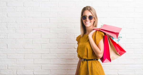 Hermosa Mujer Joven Sobre Pared Ladrillo Blanco Sosteniendo Bolsas Compras — Foto de Stock