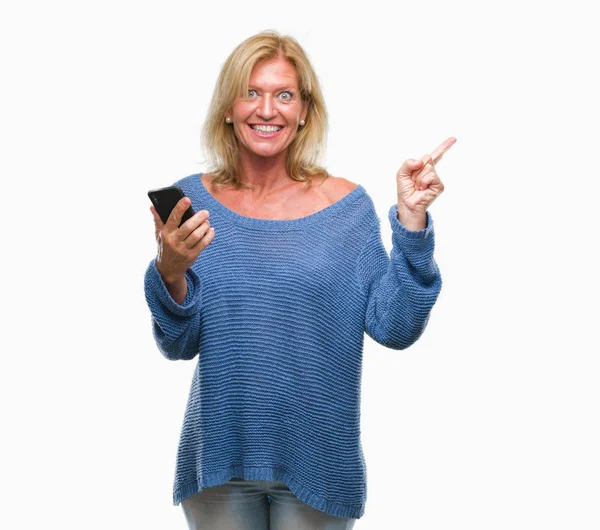 中年の金髪女性分離背景側を手と指で指している非常に満足してスマート フォンを使用してメッセージを送信します — ストック写真