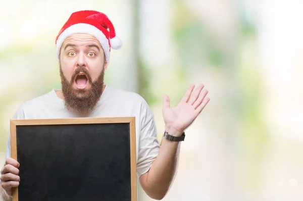 Joven Hipster Caucásico Con Sombrero Navidad Sosteniendo Pizarra Sobre Fondo —  Fotos de Stock