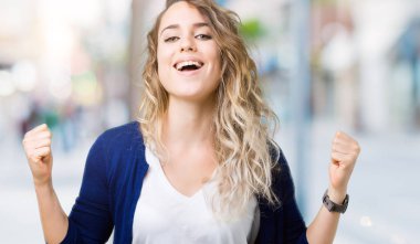 İzole arka plan kutlama üzerinde güzel sarışın genç kadın şaşırttı ve başarı için kaldırdı kollarını açarak hayret ve gözleri açık. Kazanan kavramı.