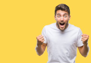 İzole arka plan kutlama üzerinde genç yakışıklı adam şaşırttı ve başarı için kaldırdı kollarını açarak hayret ve gözleri açık. Kazanan kavramı.