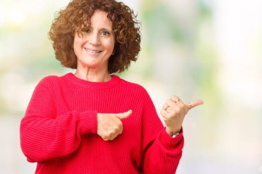 Güzel orta ager üst düzey kadın kırmızı kış kazak izole arka plan üzerinde emin gülümseyen arkasından el ve kadar başparmak ile işaret