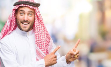 Keffiyeh gülümseyen ve iki elleri ve parmakları ile tarafına işaret kamera bakarak izole arka plan üzerinde giyen genç yakışıklı adam.