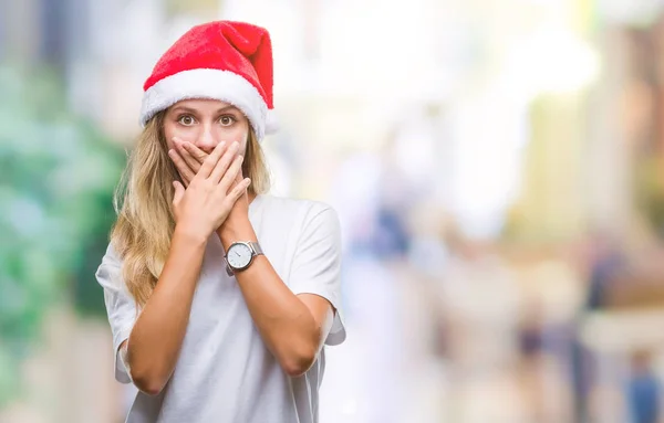 若い美しい金髪女性の孤立した背景のミスのための手で口を覆っているショックを受けた上クリスマス帽子をかぶっています 秘密の概念 — ストック写真