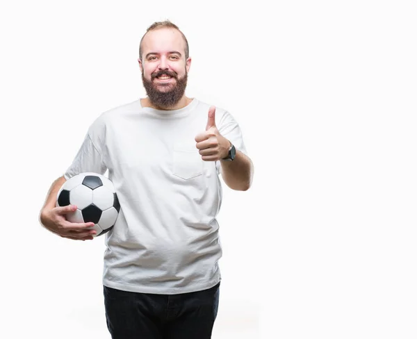サッカー サッカー ボールの上に保持している若い白人ヒップ男笑顔の サイン 優秀な兆候を親指をやって幸せなバック グラウンドを分離 — ストック写真