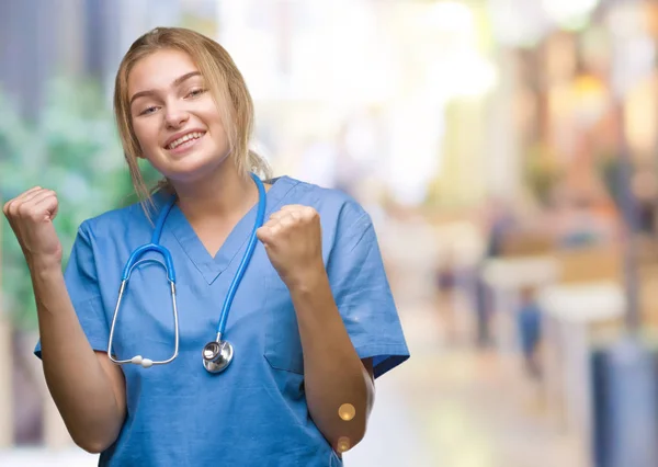 年轻的高加索医生妇女穿着外科医生制服在孤立的背景非常高兴和兴奋做优胜者姿态与胳膊举起 微笑和尖叫为成功 庆祝理念 — 图库照片